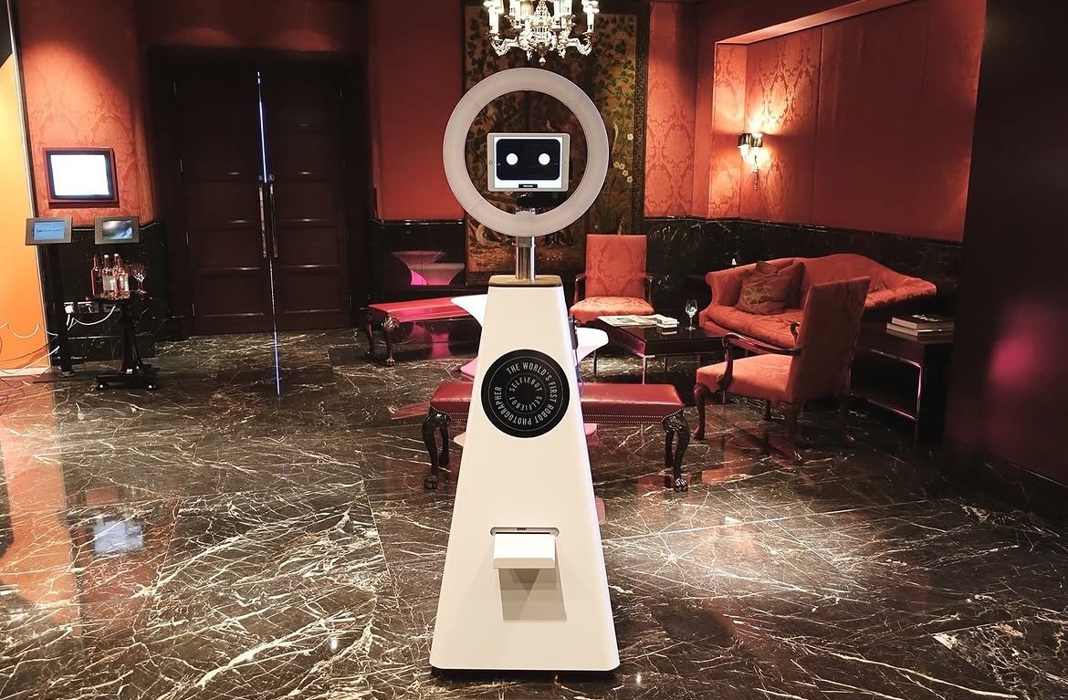 Robo Booth robotic photo booth unit glowing in an elegant red-lit room